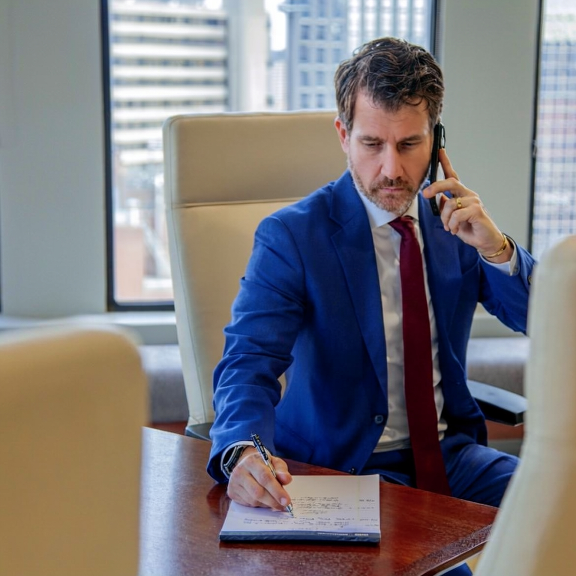 Louisville Kentucky attorney Matthew Farra speaking on phone and taking notes in law office